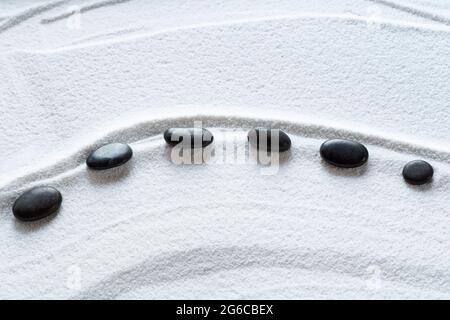 Zen black pebbles on white sand Stock Photo