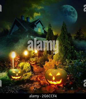 Night scene of Halloween pumpkin lanterns pathway throug mystery garden to scary haunted house Stock Photo