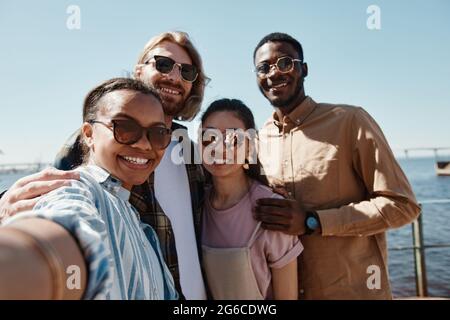 POV at diverse group of young people taking selfie outdoors in summer all wearing sunglasses Stock Photo