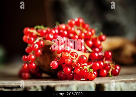 Ripe red currant berries in a bowl. Fresh red currants on dark rustic wooden table. Background with copy space. Selective focus. Stock Photo