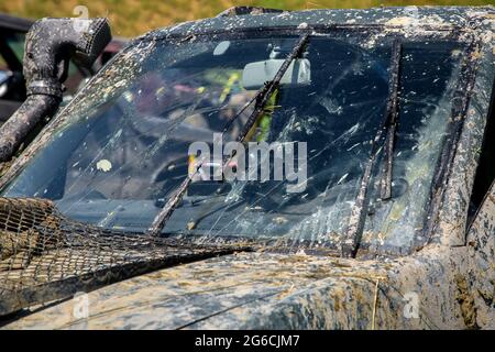 windshield wipers with washers clean the windshield from the swamp, a dirty SUV car, smeared with swamp, traveling on dirt roads, nobody. Stock Photo