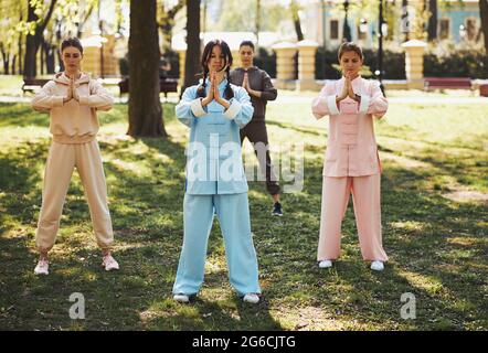 Trainer and students of qigong holding hand in praying gesture Stock Photo