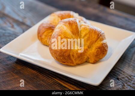 Two Croissants on White Square Plate and wooden table Stock Photo