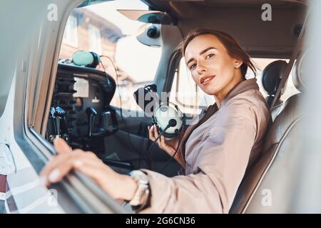Nice young woman sitting in aircraft pilot cabin Stock Photo