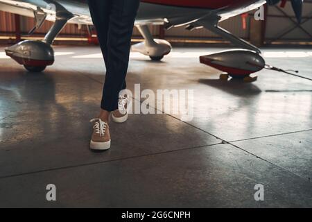 Female legs in sneakers walking down aircraft hangar Stock Photo