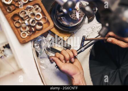 Jewelry maker using ball pein hammer for peening of ring Stock Photo