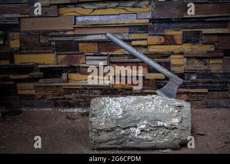 Old metal axe with the stuck in a log at walls are made of different types of wood texture background Stock Photo