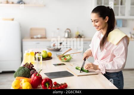 Woman cooking salad and using tablet at kitchen Stock Photo