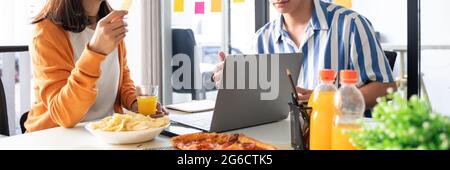 Happy business team workers talking about project and sharing meal enjoying having fun at work Having Meeting Eating Pizza and potato chips. Stock Photo