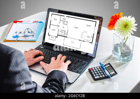 Man typing on a laptop showing an apartment plan concept Stock Photo