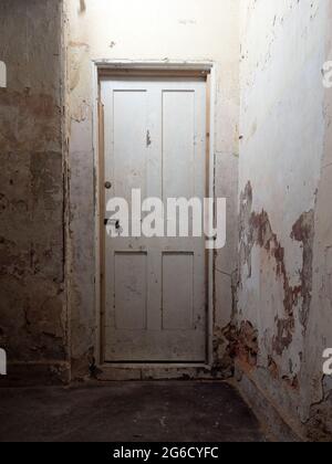 Old wooden interior door, locked, in dark corridor in abandoned old house. Stock Photo