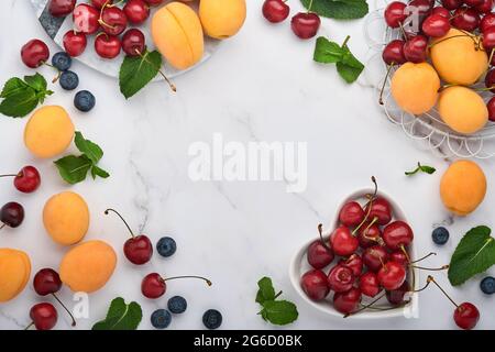 Fresh apricots, red cherry and blackberry on white marble background. Vegetarian, weight loss, clean and healthy eating concept. Top view. Copy space. Stock Photo