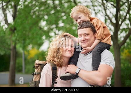 Delighted loving couple with adorable child spending time together in summer park and enjoying weekend Stock Photo