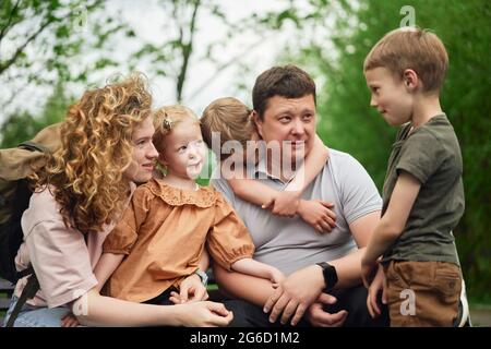 Content parents and cute kids enjoying summer weekend and spending time together in green park Stock Photo