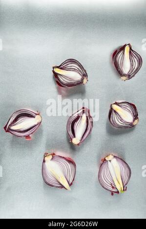 Top view minimalist style composition with halved red onion bulbs scattered randomly on light gray background Stock Photo