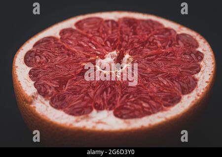 red grapefruit cut in half, still life, studio photography, fruit on a black background Stock Photo