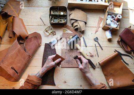 High angle view of worker working with leather and work tools at his table in workshop Stock Photo