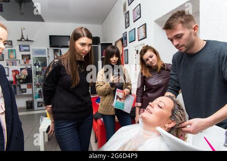 Grodno, Belarus - October 20, 2016: Keune brand technologist Artem Raychuk dyes the hair of a model on advertising workshop with the participation in Stock Photo