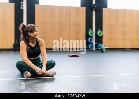 Beautiful brunette woman resting on the floor after training in the gym Stock Photo