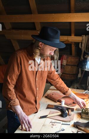 Carpenter in hat repairing the products with tools at his workplace in the workshop Stock Photo