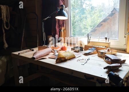 Image of workplace of carpenter with work tools and pieces of leather material on the table in workshop Stock Photo