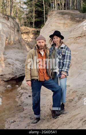 Portrait of young couple of hikers holding hands and looking at camera while standing on the rocks Stock Photo