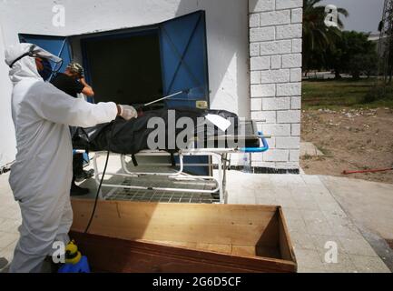 Kairouan, Tunisia. 1st Jan, 2000. (EDITORS NOTE: Image depicts death).Tunisian municipality employees prepare to place the body of a COVID-19 victim into a casket at the Ibn al-Jazzar hospital in the east-central city of Kairouan.Tunisia placed the capital Tunis and the northern town of Bizerte under a partial lockdown from until July 14 in a bid to rein in record daily coronavirus cases and deaths. Credit: Jdidi Wassim/SOPA Images/ZUMA Wire/Alamy Live News Stock Photo