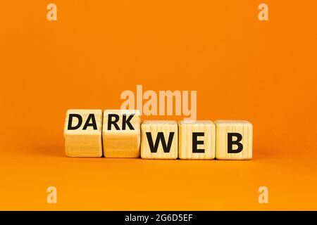 Dark web symbol. Turned wooden cubes and changed the word web to dark web. Beautiful orange background. Business, dark web concept. Copy space. Stock Photo