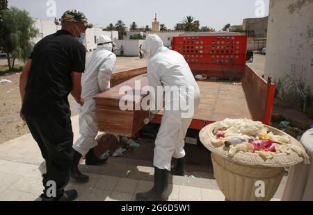 Kairouan, Tunisia. 1st Jan, 2000. (EDITORS NOTE: Image depicts death).Tunisian municipality employees carry a casket of a COVID-19 victim onto the back of a truck at the Ibn al-Jazzar hospital in the east-central city of Kairouan.Tunisia placed the capital Tunis and the northern town of Bizerte under a partial lockdown from July 14 in a bid to rein in record daily coronavirus cases and deaths. Credit: Jdidi Wassim/SOPA Images/ZUMA Wire/Alamy Live News Stock Photo