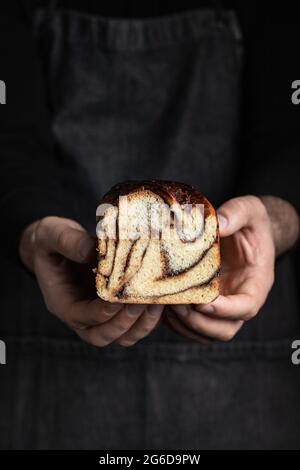 Unrecognizable crop man in black apron standing with homemade chocolate Babka dessert Stock Photo