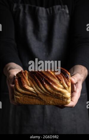 Unrecognizable crop man in black apron standing with homemade chocolate Babka dessert Stock Photo