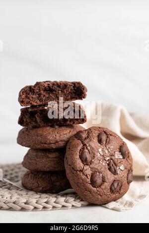 Pile of chocolate rye cookies placed on wicker plate near napkin on white background Stock Photo