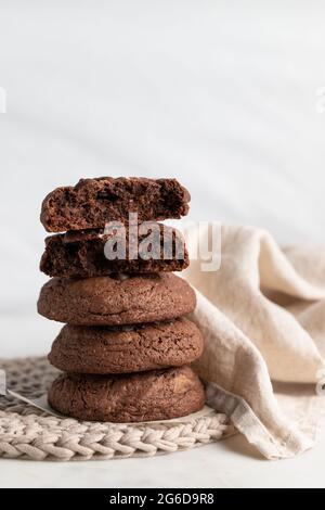 Pile of chocolate rye cookies placed on wicker plate near napkin on white background Stock Photo