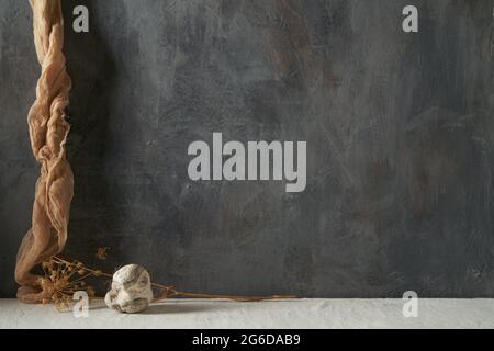 Stone and piece of cloth with dried plant on beige and gray background Stock Photo