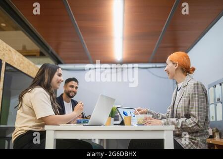 Group of focused colleagues sitting at table and working together on startup project in coworking space Stock Photo