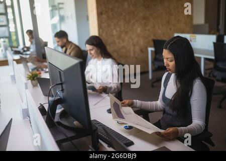 Group of focused multiracial colleagues siting at table and working on project in modern coworking space Stock Photo