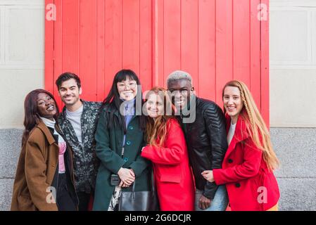 Group of excited multiracial friends having fun in city while standing looking at camera on street Stock Photo
