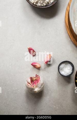 From above top view cloves of ripe garlic and small bowl of salt placed on kitchen table during food preparation Stock Photo