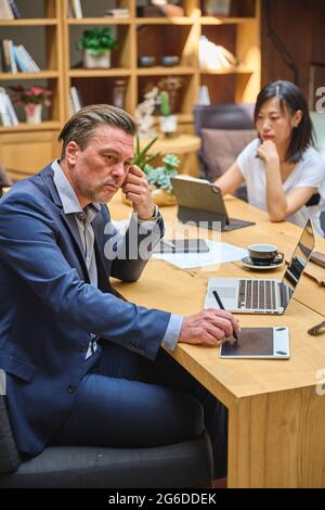 Designer at his desk working on his computer with his assistant Stock Photo