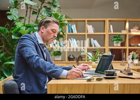 Designer at his desk working on his computer using his tablet Stock Photo