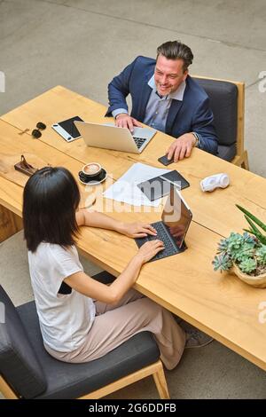 Designer at his desk working on his computer with his assistant Stock Photo