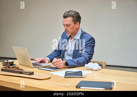 Designer at his desk working on his computer using his tablet Stock Photo