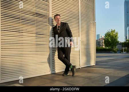 Business man standing up outside of office building in sunset time Stock Photo