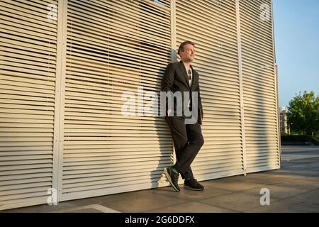 Business man standing up outside of office building in sunset time Stock Photo