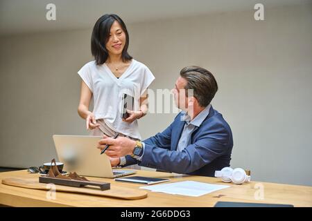 Designer at his desk working on his computer with his assistant Stock Photo