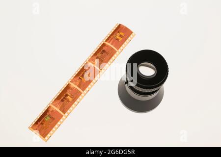 Developed 35mm colour negative film strip and loupe on light table Stock Photo