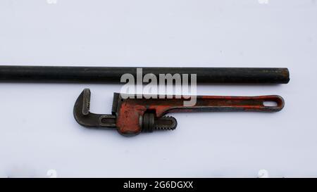 An Old Pipe Wrench and a Black Iron Pipe Stock Photo