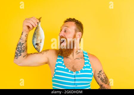 man with beard and swimsuit caught a fish Stock Photo