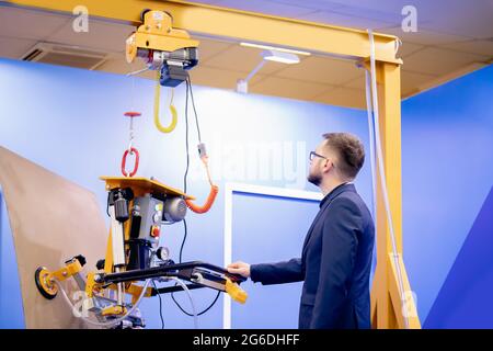 Vacuum conveyor to move flat load in factory uses Worker engineer, production industry optimization concept. Stock Photo