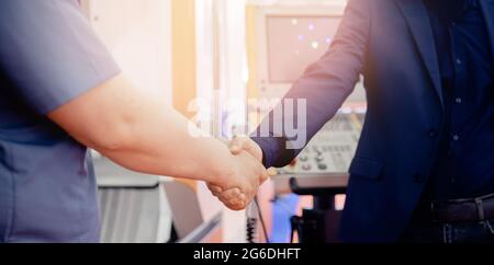 Worker engineer shaking hands with businessman at construction site background cnc control panel. Stock Photo